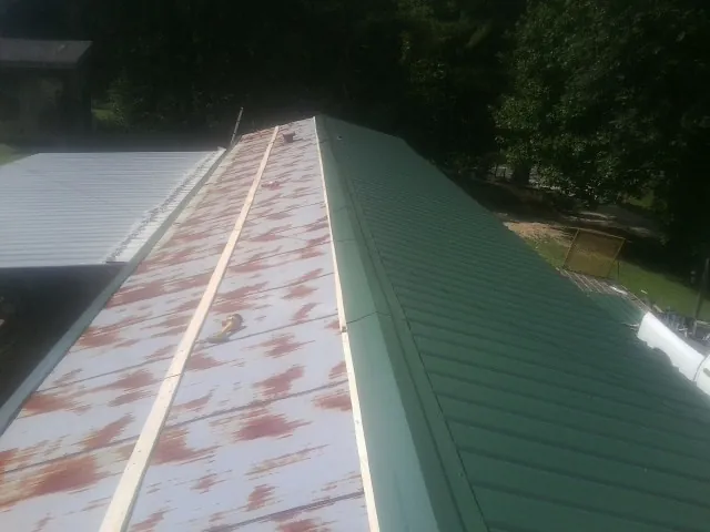 Old rusted panels beside newly installed green metal roofing — Wind Damage Roof Repair by Roofing Brothers in Paxton