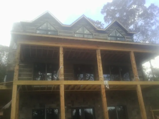 Dormers and porch framing on a large log home under construction — Roof Coating work by our crew in Paxton