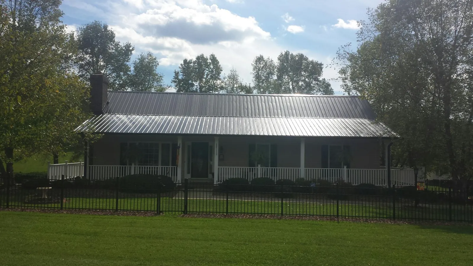 Gray metal roof on a brick ranch with a full width front porch — Gutter Guard Installation work by our crew in Paxton