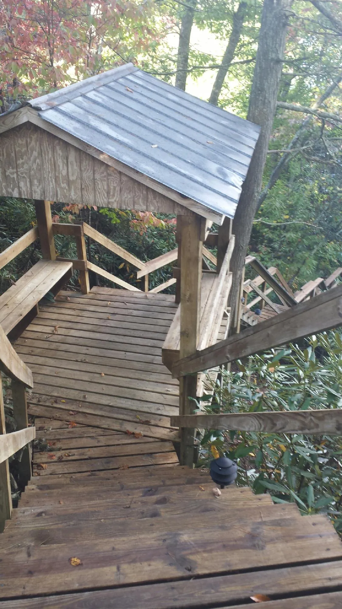 Metal roofed shelter over wooden steps on a wooded walkway — Skylight Repair & Installation work by our crew in Paxton