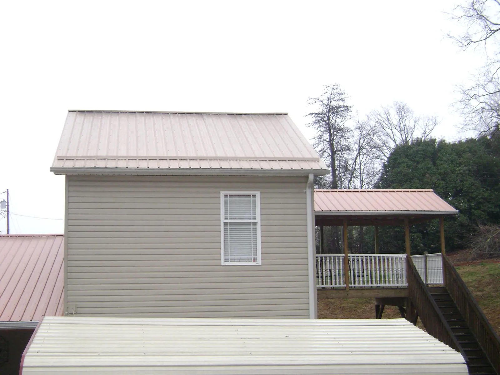 Tan metal roofs on a two story addition and attached porch, from a Roof Replacement job in Paxton