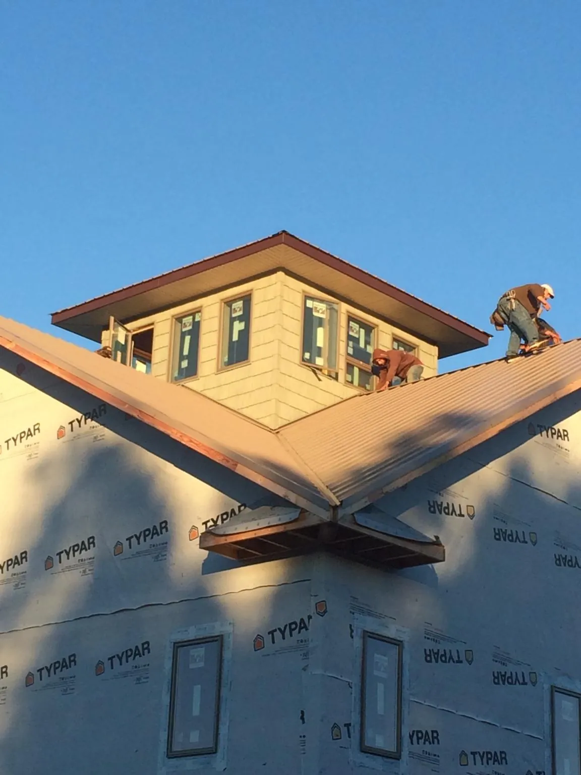 Roofers working around a rooftop cupola on a new metal roof at sunset — Roof Waterproofing in Paxton by Roofing Brothers